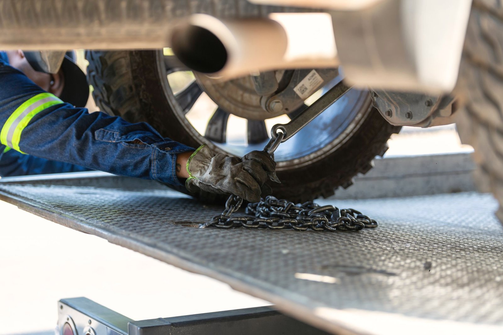 Gloved hands setting a safety chain against a tire on a flatbed deck